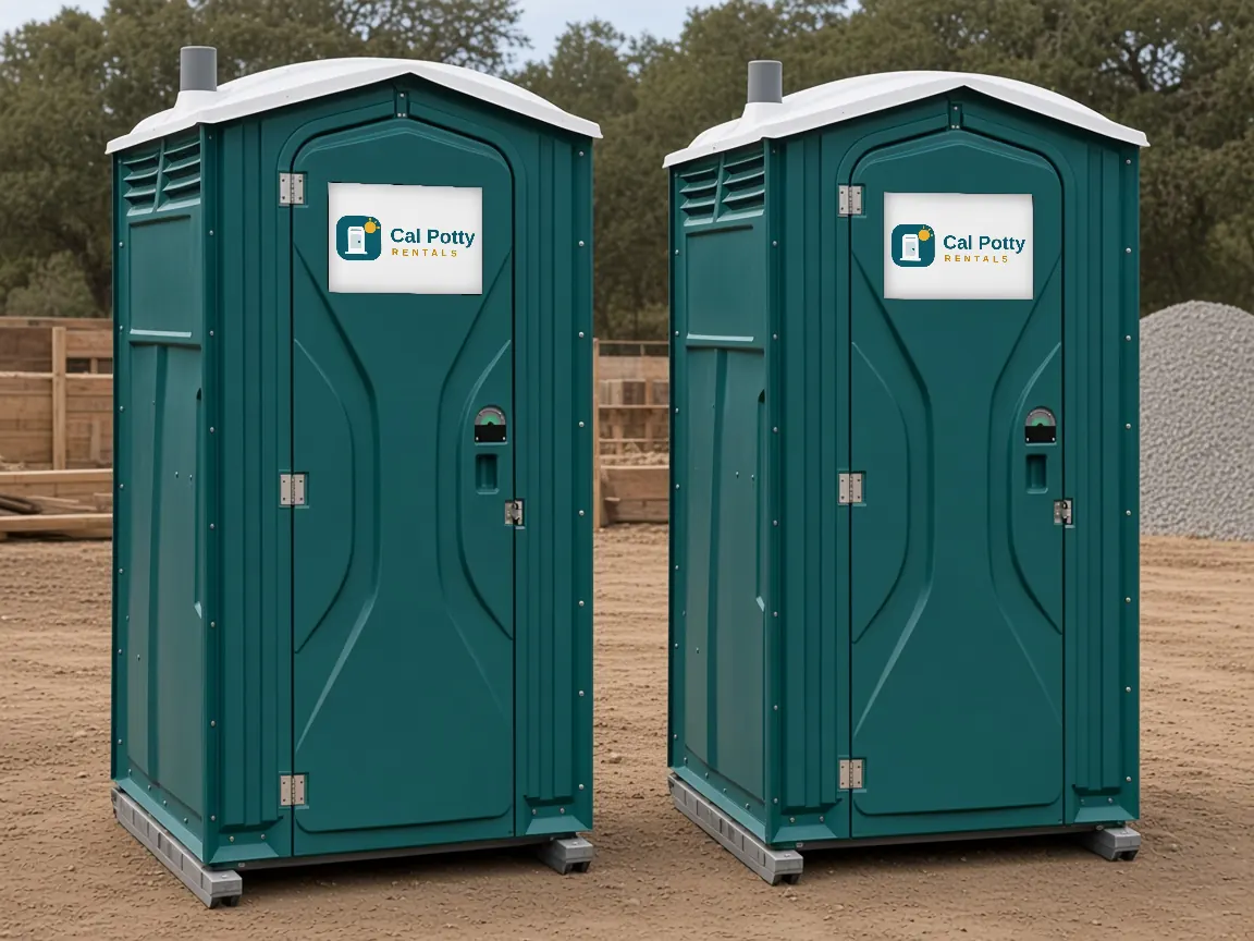 Two teal porta potties on a cleared dirt lot, an example setup for porta potty rental in Woodside
